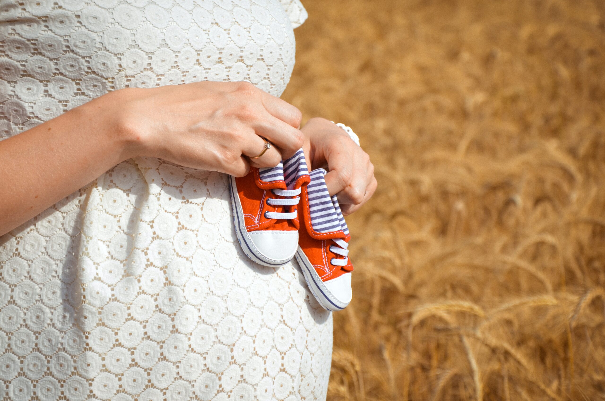 Pregnant woman carrying the shoes of a newborn or baby