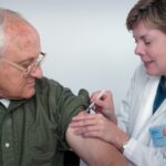 Pharmacist giving a flu shot to a senior man in Calgary for the 2026 Alberta flu vaccine campaign